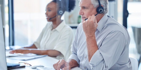 Phone call, customer service and man with headset, computer and mature agent in crm office. Tech support, contact or consultant in telemarketing callcenter for advice in online account management.