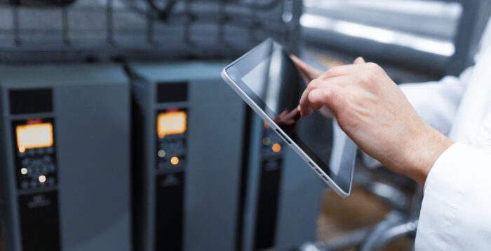 technologist with grey tablet in his hands make a set up of the production line while standing at the department of dairy factory